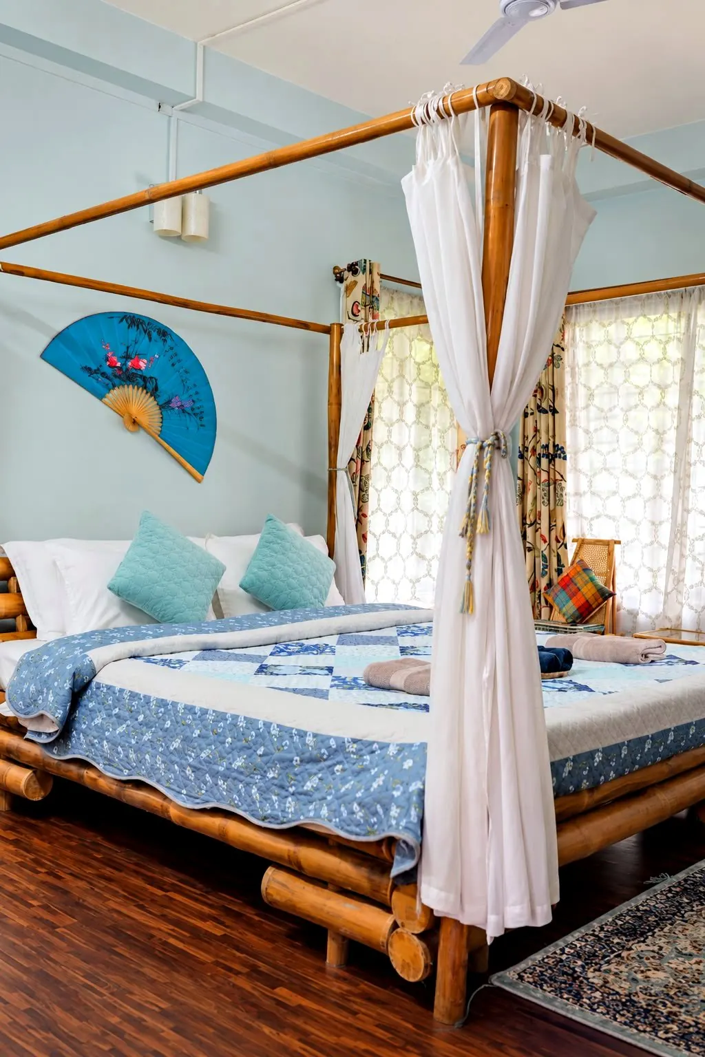 Bamboo room seen closer, with a painted fan, teal cushions and tasselled curtain ties