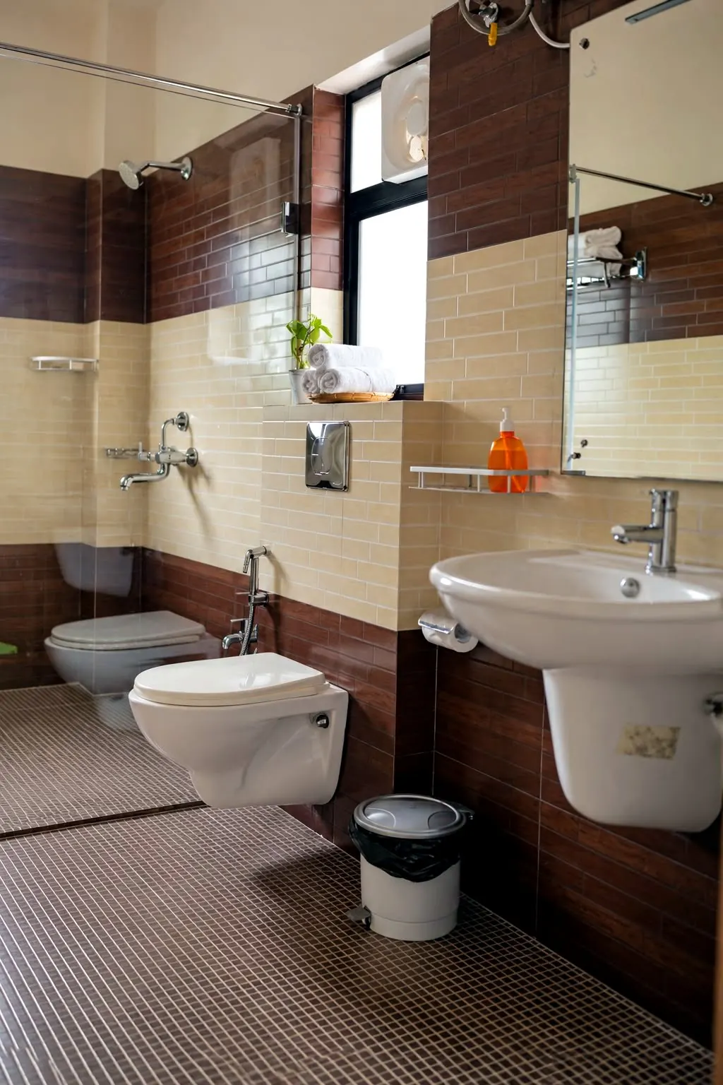 Orchid room's ensuite bathroom, tiled in warm brown and cream with a wall-hung basin